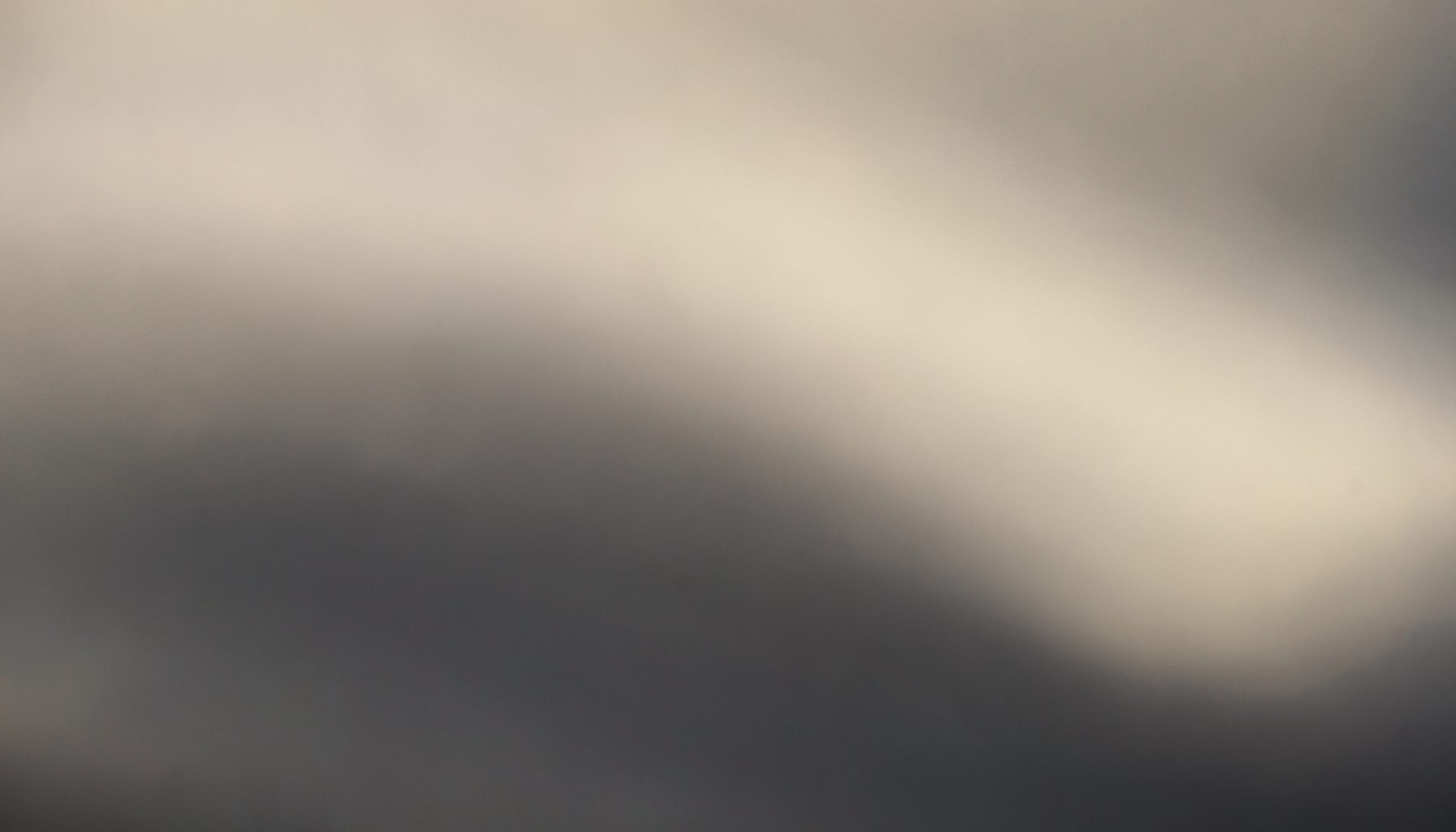 Abstract composition of soft diffused light across a smooth surface, muted beige and charcoal tones, evoking a clean medical-aesthetic atmosphere