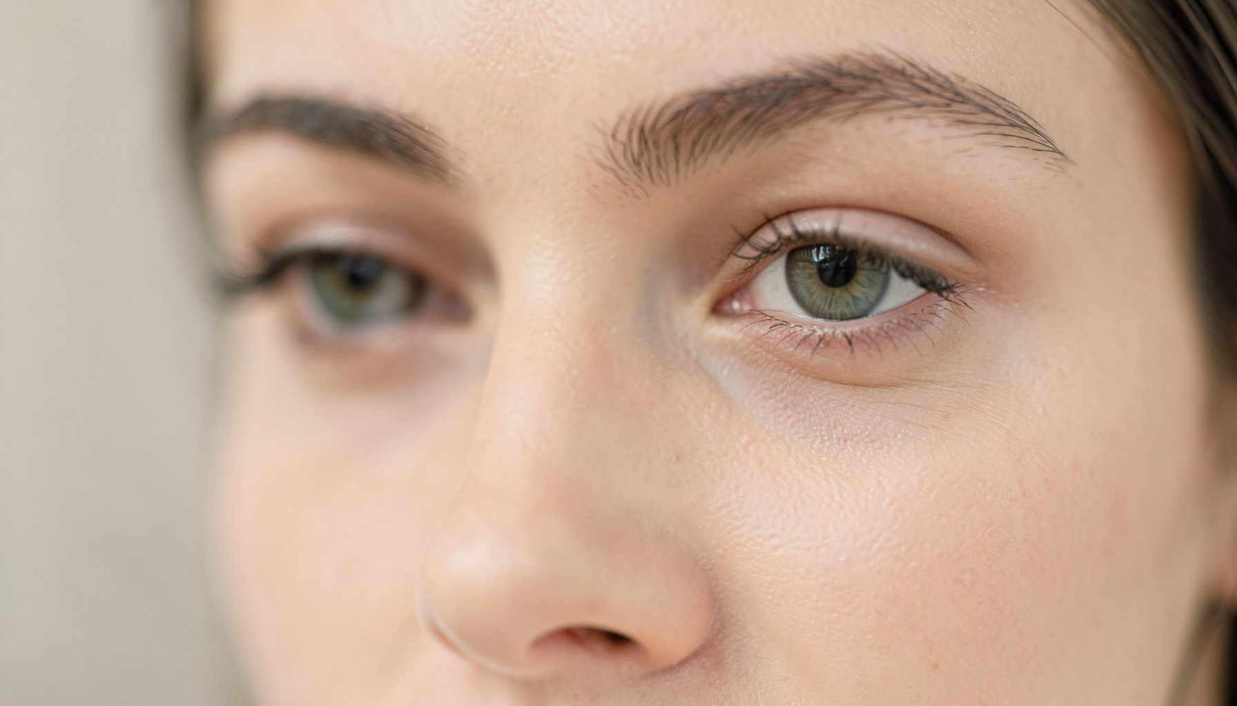 Soft-focus close-up of a serene eye area with subtle shadowing, warm neutral tones, and a calm clinical ambiance